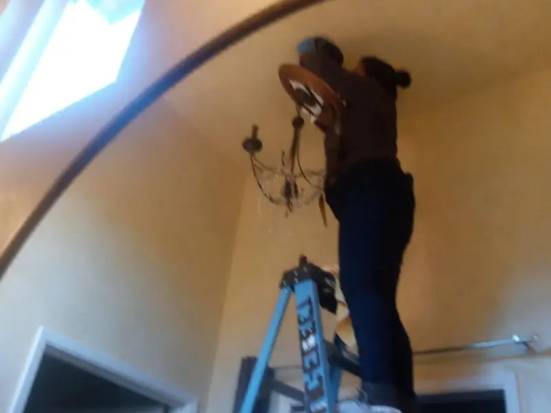 Electrician installing a chandelier in a Bridgeport residence